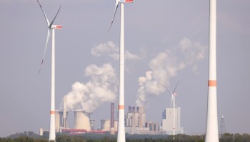 In the foreground, wind turbines. In the background, steam rises from cooling towers at a coal-fired power plant in Germany.