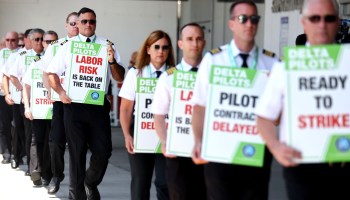 Delta Air Lines pilots dressed in uniform walk in a line holding signs that read "Ready to Strike" at Los Angeles International Airport on June 30.