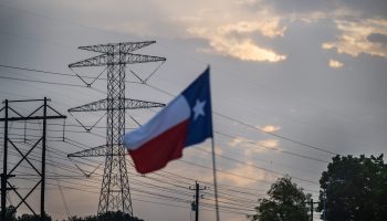 The Texas flag with power transmission towers in the background.