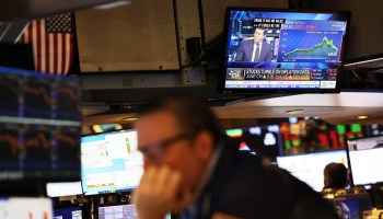 Financial news is seen on a television screen as traders work on the floor of the New York Stock Exchange during morning trading on July 13, 2022 in New York City.