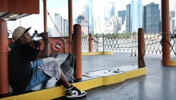 A man takes a drink of water while riding on the Staten Island Ferry on a sweltering afternoon.