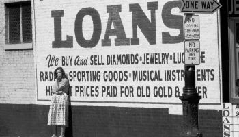 A woman standing in front of a loan company's advertisement painted on a wall in Louisville, Kentucky circa 1955