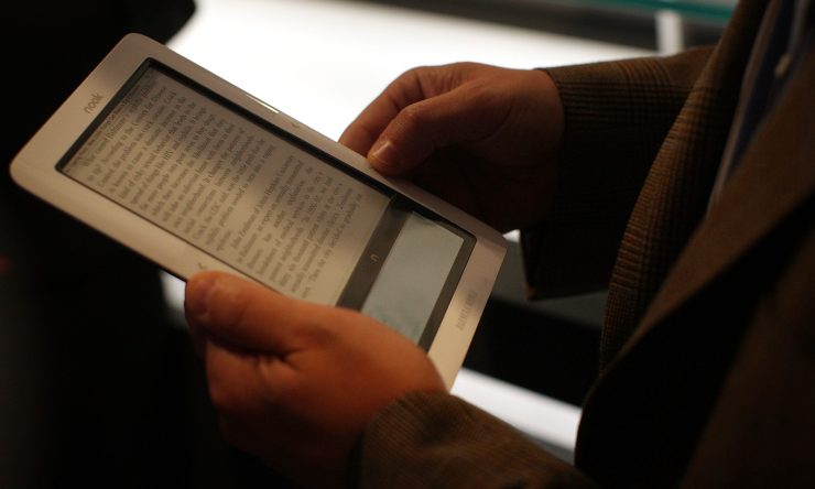 Someone holds a nook wireless reader with text.