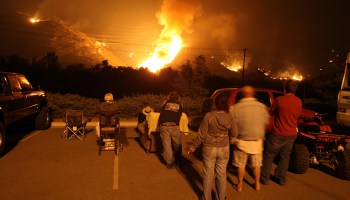 Evacuated residents watch backfires burn a hillside in California.