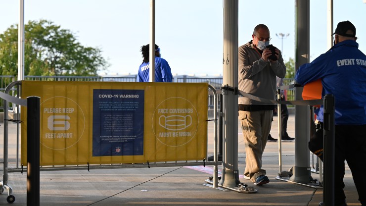 A man walks through a metal detector at a football stadium.