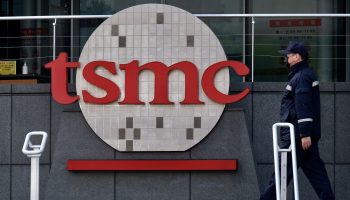 A security guard walks past a large logo for Taiwan Semiconductor Manufacturing Company