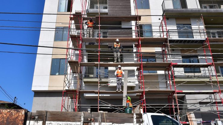 Construction workers pass planks of wood during the construction of new apartments.