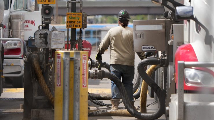 A man unloads crude oil from a tanker to process it into gasoline.