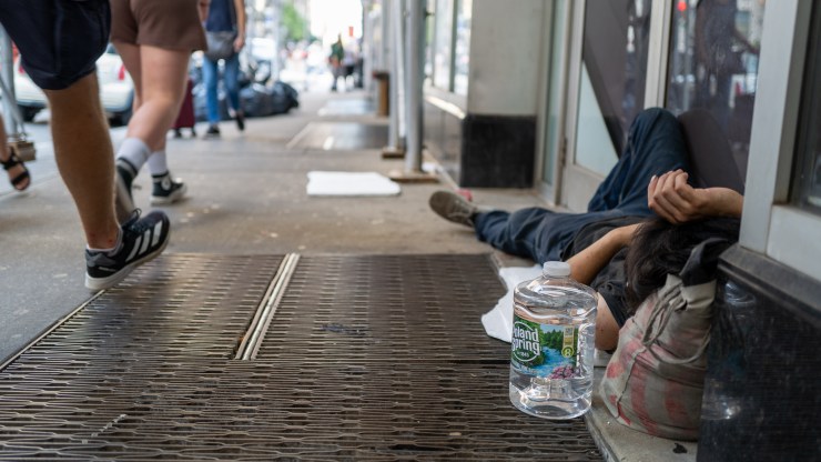 A homeless man sleeps on a Manhattan street during a heat wave.
