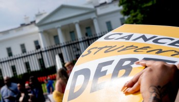 An activist holds a Cancel Student Debt sign at a rally in front of the White House.