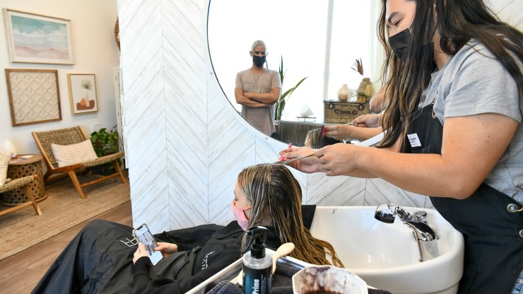 A hairstylist colors a client's hair.