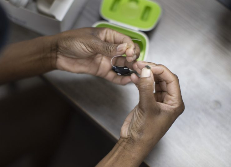 A patient holds a hearing aid in her hands.