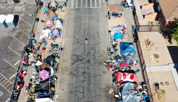 An aerial view of people gathered near a homeless encampment on the sidewalks in the afternoon heat on July 2022 in Phoenix.