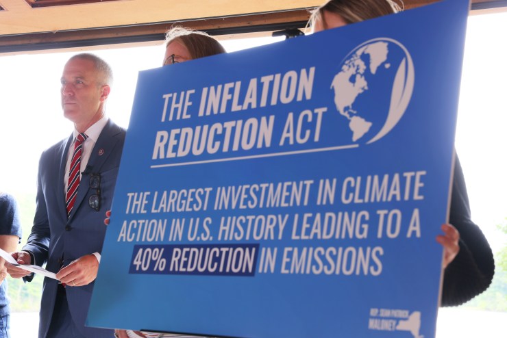 A woman holding up a blue poster of The Inflation Reduction Act