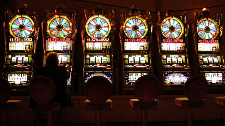 A customer plays on one of a row of slot machines.