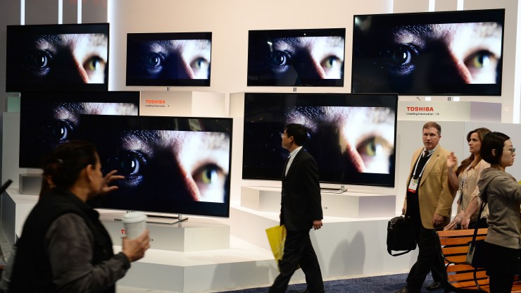 People walk past a 4K TV display.