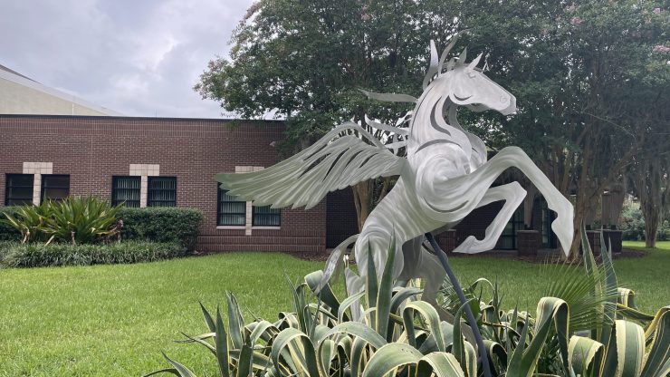 A metal statue of Pegasus emerges from greenery.