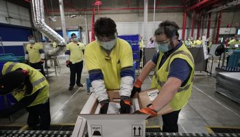 Workers pack boxes in a factory.