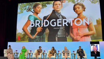 Panelists sit on stage, behind them a screen projects a photo from the hit Netflix show "Bridgerton."