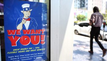 A sign in a store window with an image of Uncle Sam says "We Want You!" with information about job opportunities