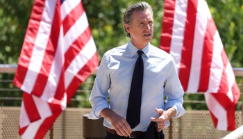California Gov. Gavin Newsom is seen in front of American flags.