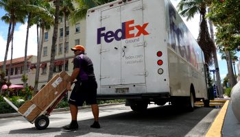 A FedEx worker pushes a package in front of a FedEx truck