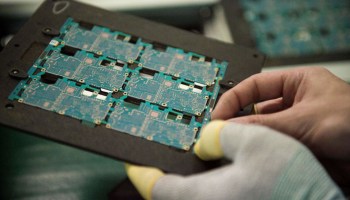 In this picture taken on May 8, 2017, smartphone chip component circuits are handled by a worker at the Oppo factory in Dongguan.