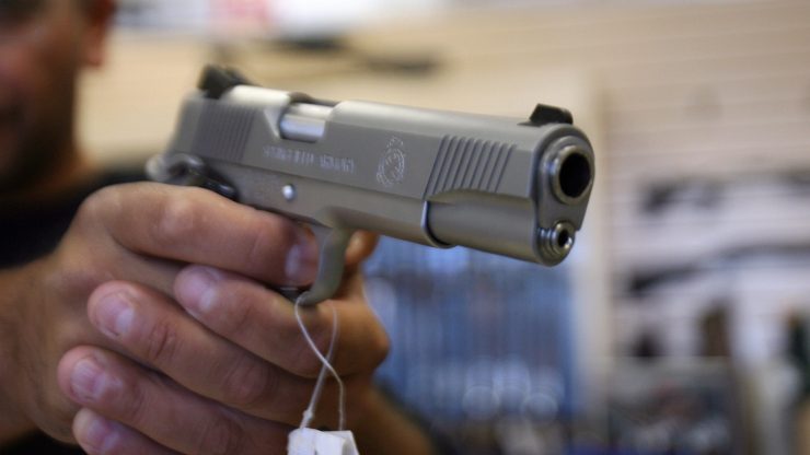 A person holds a handgun with a price tag on it.