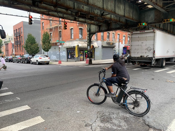 A delivery person rides an e-bike on a road in Brooklyn.