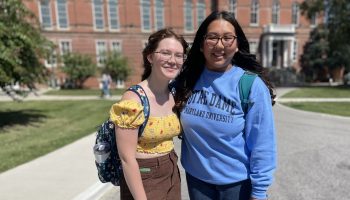 Two college students stand with their arms around each other on the campus of Notre Dame of Maryland.