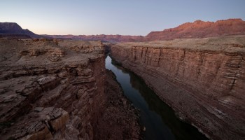 The Colorado River flows through a steep canyon of red rock in Arizona.