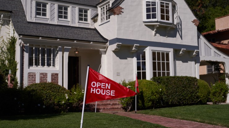An open house sign sits in front of a white house.