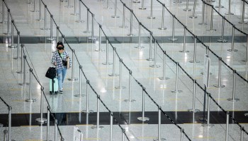 A lone woman walks between line dividers at the Hong Kong International Airport in September.