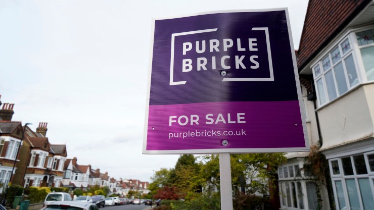 A Purple Bricks for sale sign is posted outside a two-level home with a bay window in south London on Oct. 3.