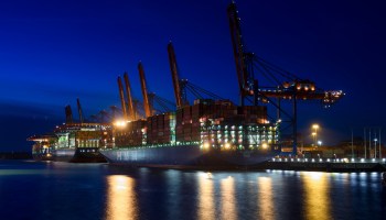 A container ship docked at Hamburg Port in Germany just after sunset.