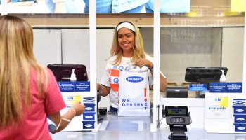 A cashier at Old Navy hands a customer a bag