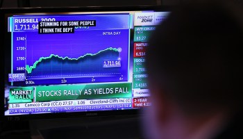 A traders looks at financial news on a television while working on the floor of the New York Stock Exchange.