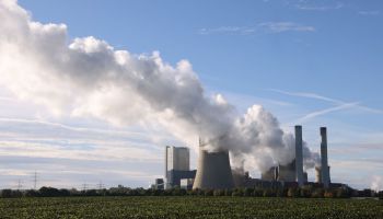 Steam rises from cooling towers of coal power plants.