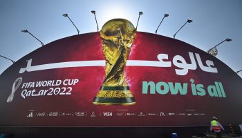 A worker walks in front of a Qatar 2022 FIFA World Cup football tournament billboard in Doha on October 29, 2022. (Photo by Gabriel BOUYS / AFP) (Photo by GABRIEL BOUYS/AFP via Getty Images)