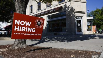 A "Now Hiring" sign in front of a Chipotle restaurant.