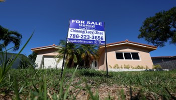 A 'For Sale' sign is posted on the front lawn of a single-family home in Hollywood, Florida.