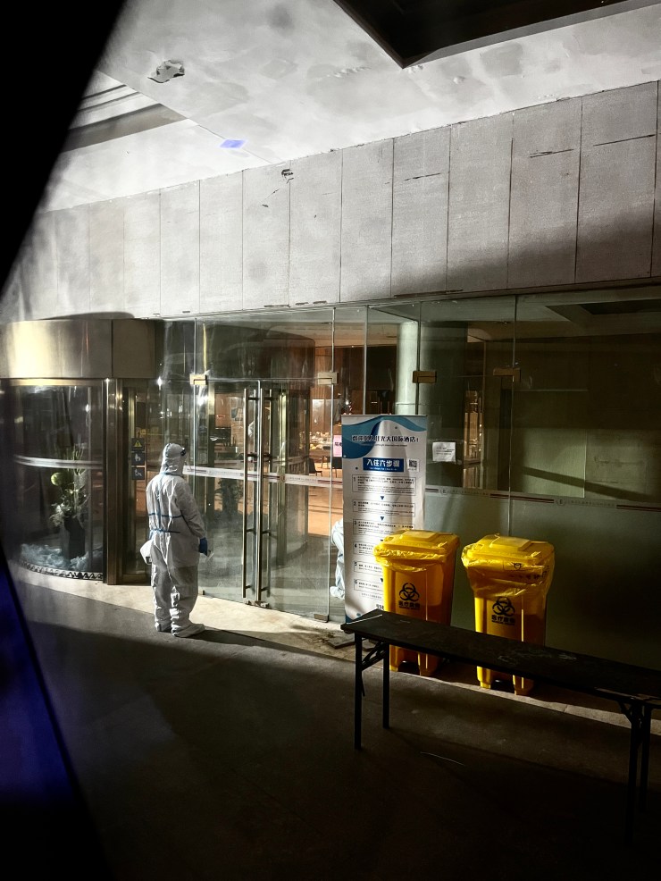 A pandemic worker stands outside a quarantine hotel in Shanghai with a bus full of grumpy passengers waiting behind him.  It usually takes 4-6 hours after arrival for incoming travelers to reach their quarantine hotels.  (Courtesy of Pack)