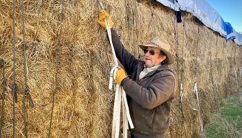 Tom Johnston takes the tarp of his hay stack to prep it for customers.