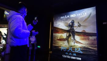 A man in front of a poster of "Avatar: The Way of Water" in Shanghai.