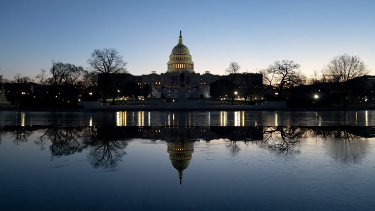 The U.S. Capitol is seen in a reflection pool at dawn.