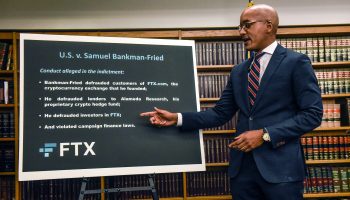 A man points to a poster board outlining the indictment of FTX founder Samuel Bankman-Fried