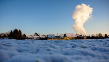 Snow lies in a residential area while smoke rises from the chimneys of a coal-fired power plant in the background in Korbetha near Halle, Germany, on a sub-zero day in December.
