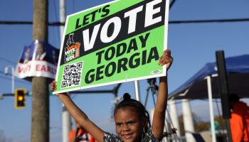 ATLANTA, GEORGIA - NOVEMBER 29: Local resident Reniya Weekes holds a sign to encourage people to vote early outside a polling station on November 29, 2022 in Atlanta, Georgia. Early voting has started in select Georgia counties for a special runoff election days after the Georgia Supreme Court rejected an emergency request from Republicans to block counties from offering early voting. (Photo by Alex Wong/Getty Images)