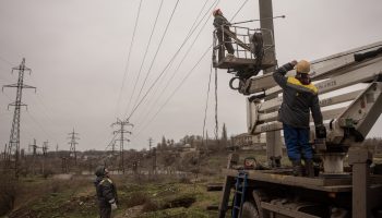 Electricity workers from a team brought in from Odessa and wearing bulletproof vests and helmets work to fix a high-voltage power line in Kherson, Ukraine.