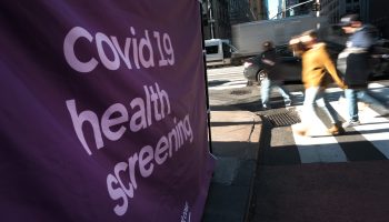 Pedestrians walk past a COVID screening site in New York City.